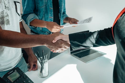 pexels-photo-7979604-7979604 - MIEUX AGIR Two business professionals engaging in a handshake agreement in a modern office environment with documents present.